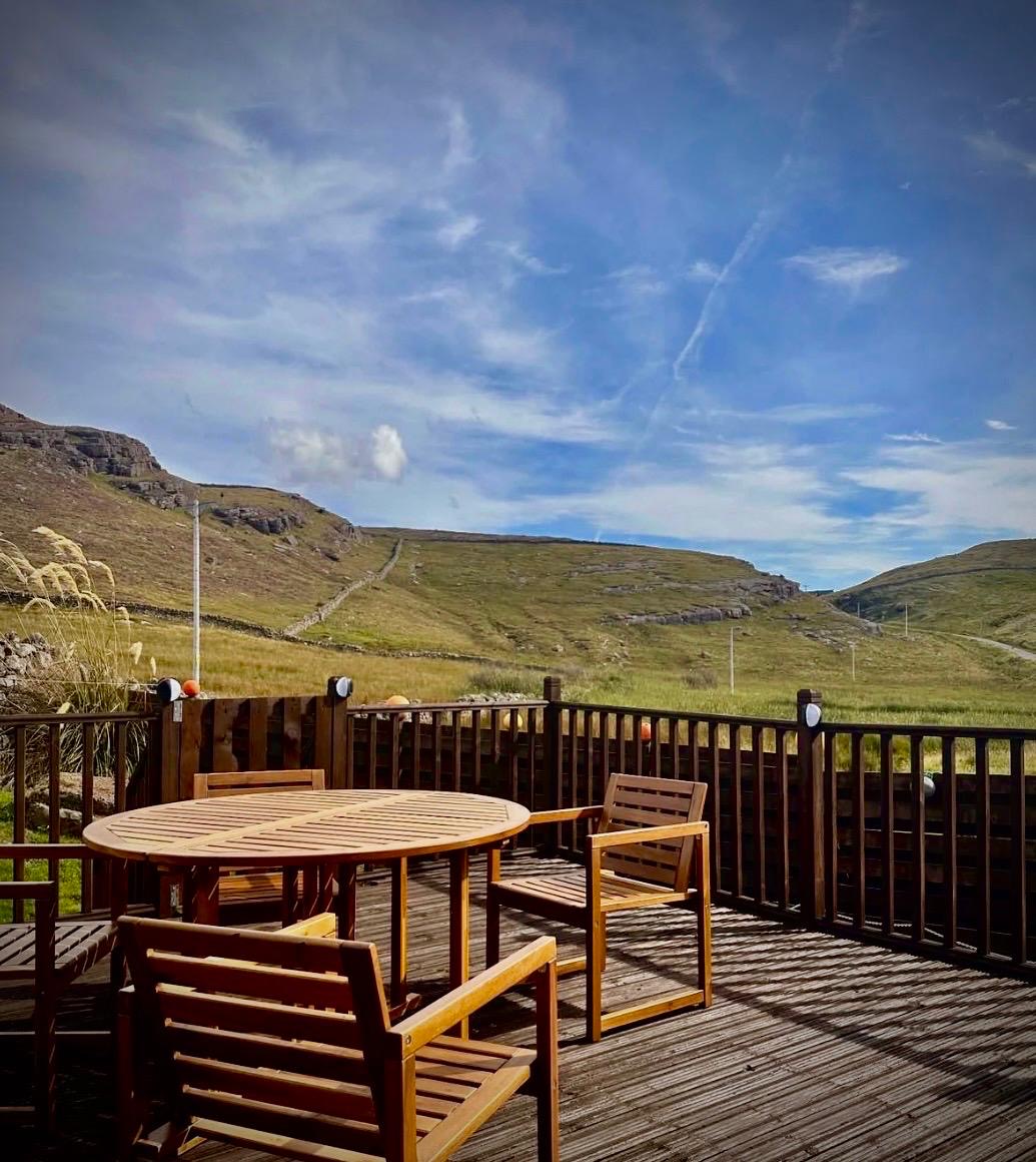 Outdoor table and chairs on the decking with open Highland views